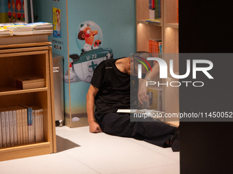 A man is resting on the floor at a bookstore in Shanghai, China, on August 2, 2024, as high temperatures are persisting for the upcoming day...