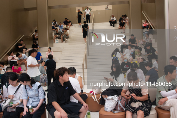 People are resting at a Huawei store in Shanghai, China, on August 2, 2024, as high temperatures are persisting for the upcoming days in Sha...