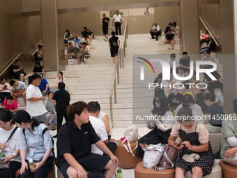 People are resting at a Huawei store in Shanghai, China, on August 2, 2024, as high temperatures are persisting for the upcoming days in Sha...