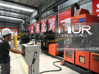 Workers are operating a machine to cast a sleeper at the Nanchang-Jiujiang Intercity Railway's Yongrepair sleeper yard in Jiujiang, China, o...