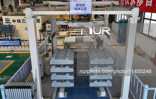 Workers are operating a machine to cast a sleeper at the Nanchang-Jiujiang Intercity Railway's Yongrepair sleeper yard in Jiujiang, China, o...