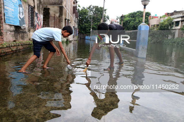 Boys are fishing on a flooded street during the heavy monsoon rain in Kolkata, India, on August 2, 2024. 