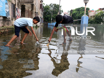 Boys are fishing on a flooded street during the heavy monsoon rain in Kolkata, India, on August 2, 2024. (