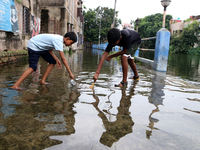 Boys are fishing on a flooded street during the heavy monsoon rain in Kolkata, India, on August 2, 2024. (