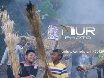 Children are carrying live hay straw as they are taking part in the immolation ceremony of demon deity Ghantakarna to veer off bad omens and...