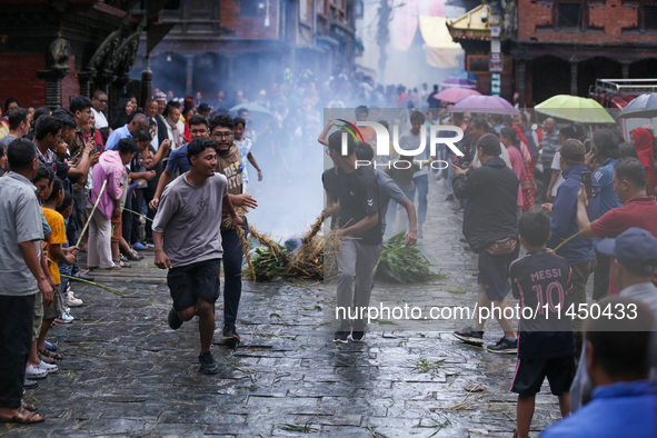 People are dragging the effigy of the demon deity Ghantakarna after setting it on fire to veer off bad omens and ward off evil spirits in Bh...