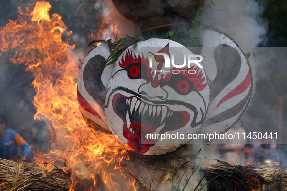 People are setting the effigy of the demon deity Ghantakarna on fire after dragging it down to a crossroad in Bhaktapur, Nepal, on August 2,...