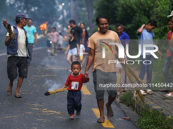 A child is carrying a live hay straw as he walks along with his father during the immolation ceremony of demon deity Ghantakarna to veer off...