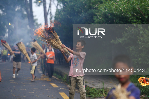 Children are carrying live hay straw as they are taking part in the immolation ceremony of demon deity Ghantakarna to veer off bad omens and...