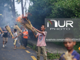 Children are carrying live hay straw as they are taking part in the immolation ceremony of demon deity Ghantakarna to veer off bad omens and...