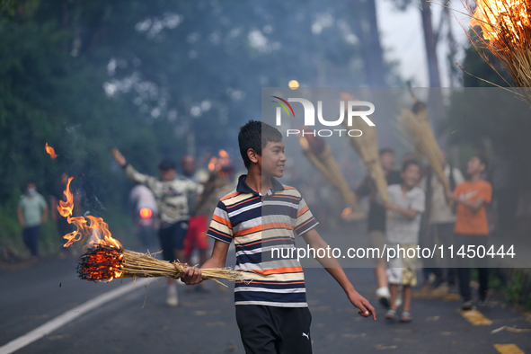 Children are carrying live hay straw as they are taking part in the immolation ceremony of demon deity Ghantakarna to veer off bad omens and...