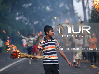 Children are carrying live hay straw as they are taking part in the immolation ceremony of demon deity Ghantakarna to veer off bad omens and...