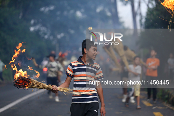 Children are carrying live hay straw as they are taking part in the immolation ceremony of demon deity Ghantakarna to veer off bad omens and...