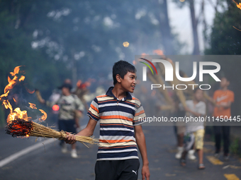 Children are carrying live hay straw as they are taking part in the immolation ceremony of demon deity Ghantakarna to veer off bad omens and...