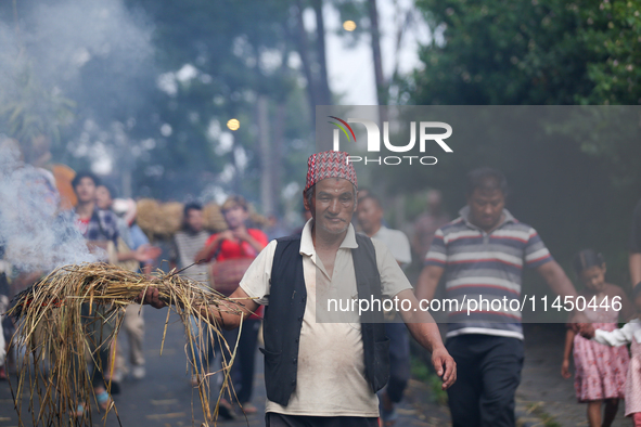 An elderly man is carrying live hay straw as he takes part in the immolation ceremony of the demon deity Ghantakarna to ward off bad omens a...