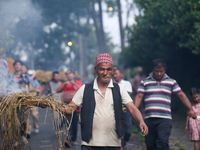 An elderly man is carrying live hay straw as he takes part in the immolation ceremony of the demon deity Ghantakarna to ward off bad omens a...