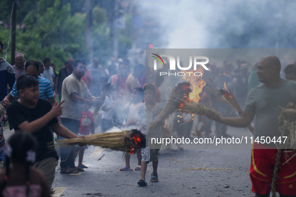 Children are carrying live hay straw as they are taking part in the immolation ceremony of demon deity Ghantakarna to veer off bad omens and...