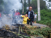 A man is swinging his child over the burning effigy of the demon deity Ghantakarna to veer off bad omens and ward off evil spirits in Bhakta...