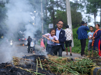 A man is swinging his child over the burning effigy of the demon deity Ghantakarna to veer off bad omens and ward off evil spirits in Bhakta...