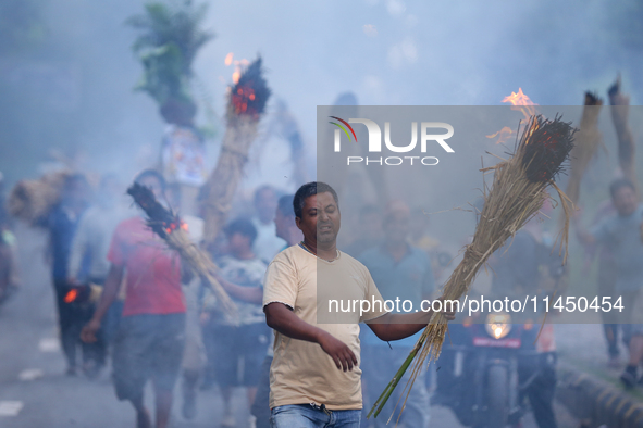 A man is carrying live hay straw as he takes part in the immolation ceremony of demon deity Ghantakarna to veer off bad omens and ward off e...