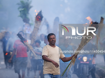 A man is carrying live hay straw as he takes part in the immolation ceremony of demon deity Ghantakarna to veer off bad omens and ward off e...