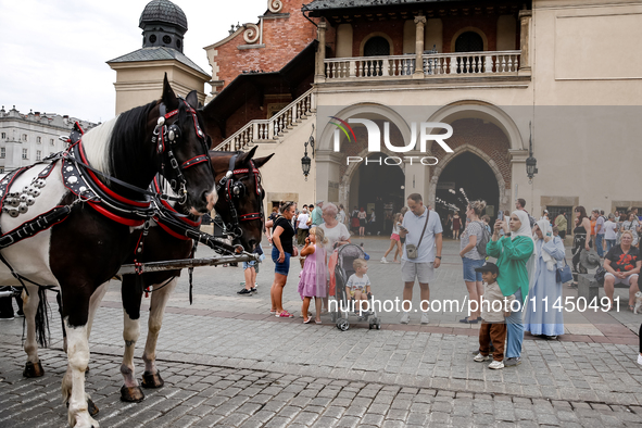 Visitors walk stand by hourse carriage during a festival of UNESCO enlisted site of historical trade centre in Krakow, Poland on August 2, 2...