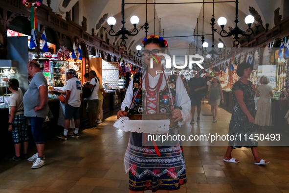 A woman dressed in traditional Krakow clothes walks along stalls with hand made local souvenirs during a festival of UNESCO enlisted site of...