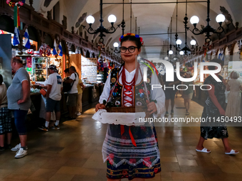 A woman dressed in traditional Krakow clothes walks along stalls with hand made local souvenirs during a festival of UNESCO enlisted site of...