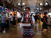 A woman dressed in traditional Krakow clothes walks along stalls with hand made local souvenirs during a festival of UNESCO enlisted site of...