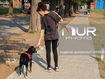 A woman is giving her dog water to keep it hydrated in the high temperatures in Buenos Aires, Argentina, on August 2, 2024. (