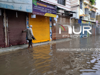 A person is walking on a water-logged street in Kolkata, India, on August 3, 2024. (