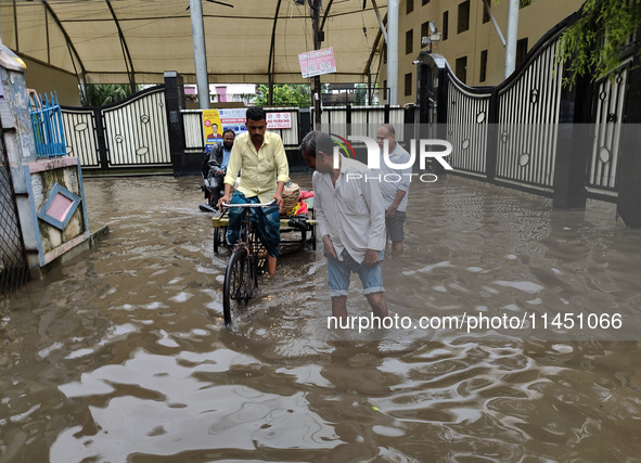 People are walking on a waterlogged street after heavy rains in Kolkata, India, on August 3, 2024. 