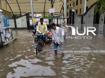 People are walking on a waterlogged street after heavy rains in Kolkata, India, on August 3, 2024. (