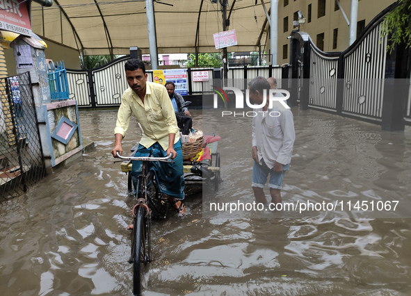 People are walking on a waterlogged street after heavy rains in Kolkata, India, on August 3, 2024. 