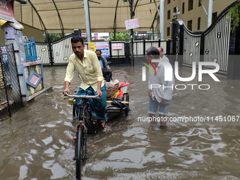 People are walking on a waterlogged street after heavy rains in Kolkata, India, on August 3, 2024. (