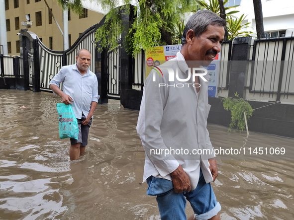 People are walking on a waterlogged street after heavy rains in Kolkata, India, on August 3, 2024. 