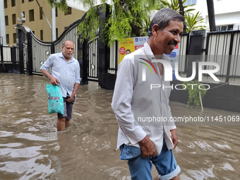 People are walking on a waterlogged street after heavy rains in Kolkata, India, on August 3, 2024. (