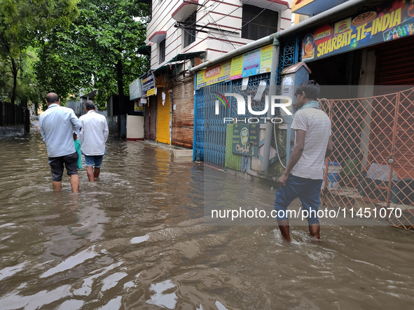 People are walking on a waterlogged street after heavy rains in Kolkata, India, on August 3, 2024. 