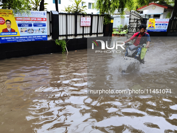 A man is riding a bike in a waterlogged street after heavy rains in Kolkata, India, on August 3, 2024. 