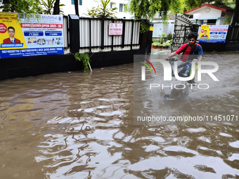 A man is riding a bike in a waterlogged street after heavy rains in Kolkata, India, on August 3, 2024. (