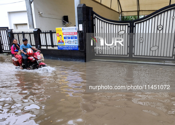 A man is riding a bike in a waterlogged street after heavy rains in Kolkata, India, on August 3, 2024. 