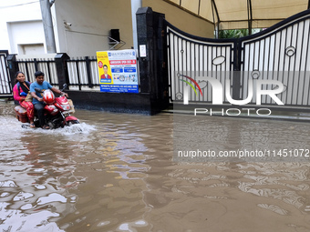 A man is riding a bike in a waterlogged street after heavy rains in Kolkata, India, on August 3, 2024. (