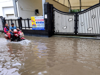 A man is riding a bike in a waterlogged street after heavy rains in Kolkata, India, on August 3, 2024. (