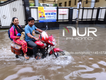 A man is riding a bike in a waterlogged street after heavy rains in Kolkata, India, on August 3, 2024. (