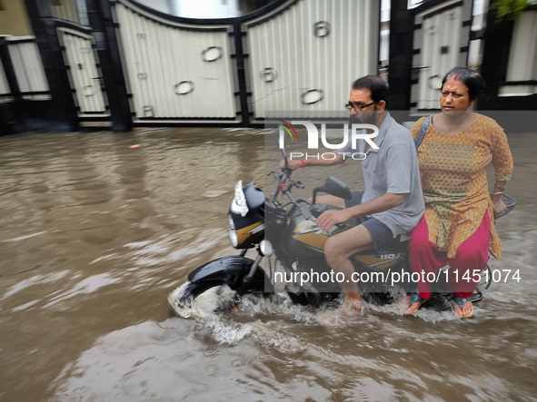 A man is riding a bike in a waterlogged street after heavy rains in Kolkata, India, on August 3, 2024. 