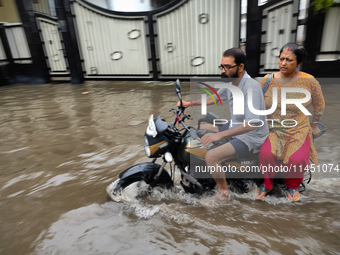 A man is riding a bike in a waterlogged street after heavy rains in Kolkata, India, on August 3, 2024. (