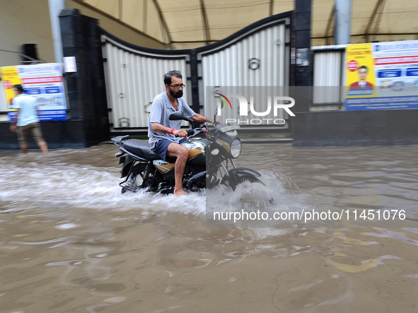 A man is riding a bike in a waterlogged street after heavy rains in Kolkata, India, on August 3, 2024. 