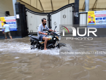 A man is riding a bike in a waterlogged street after heavy rains in Kolkata, India, on August 3, 2024. (