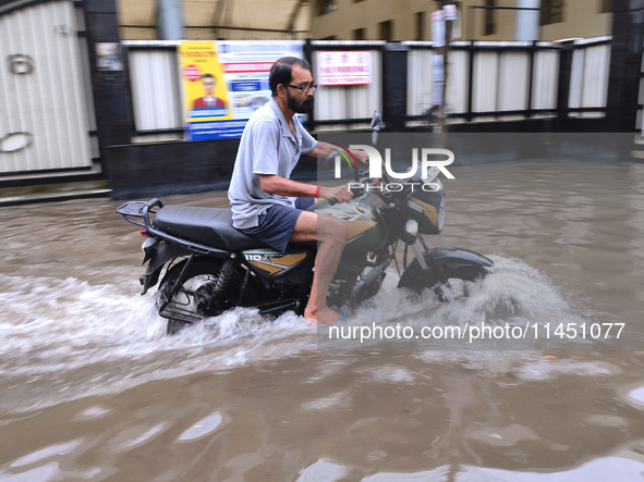 A man is riding a bike in a waterlogged street after heavy rains in Kolkata, India, on August 3, 2024. 