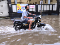 A man is riding a bike in a waterlogged street after heavy rains in Kolkata, India, on August 3, 2024. (